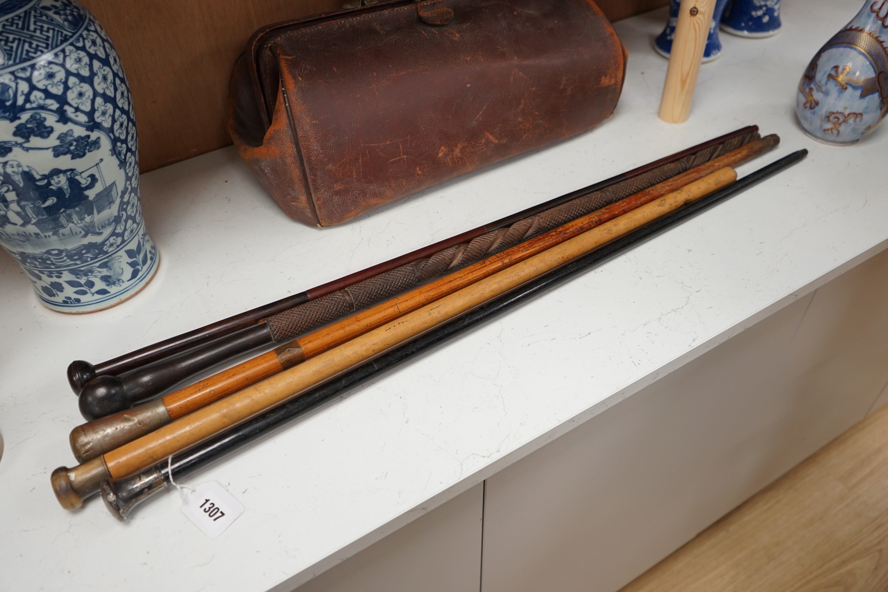 A collection of five walking sticks including one silver mounted and a Gladstone bag